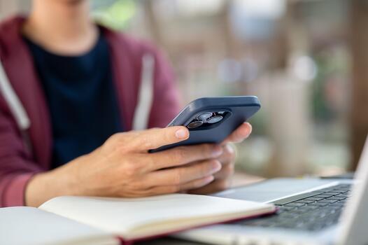 Hands resting beside a phone placed face down next to an open notebook