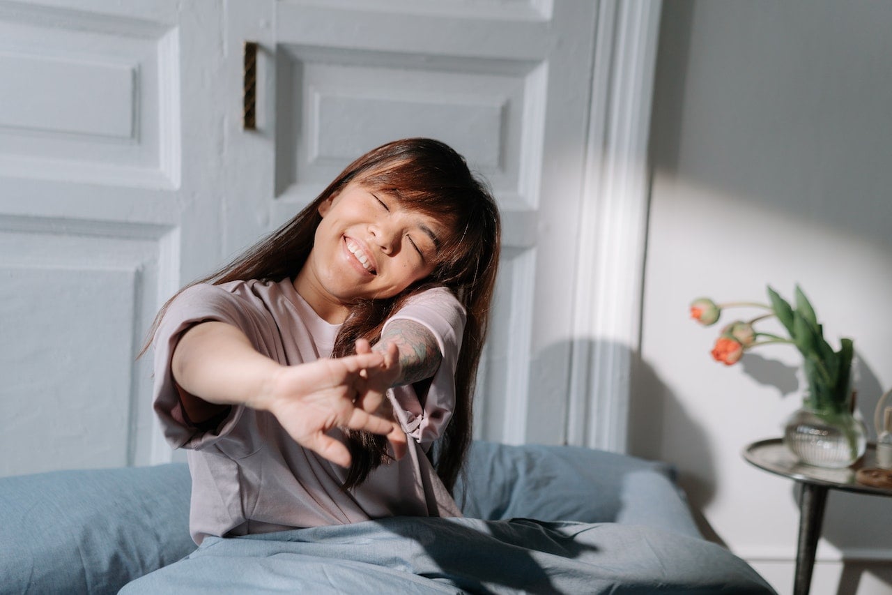 Person stretching gently beside a sunlit window during a calm morning routine